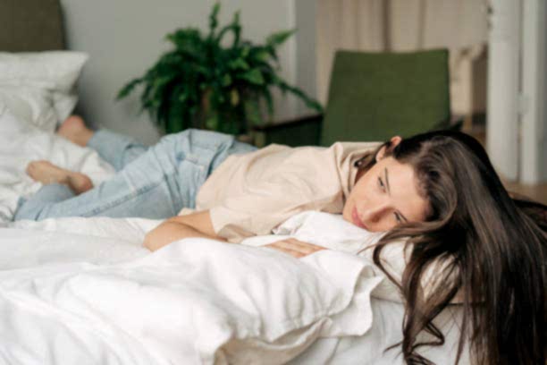 Depressed sad young woman lying on bed